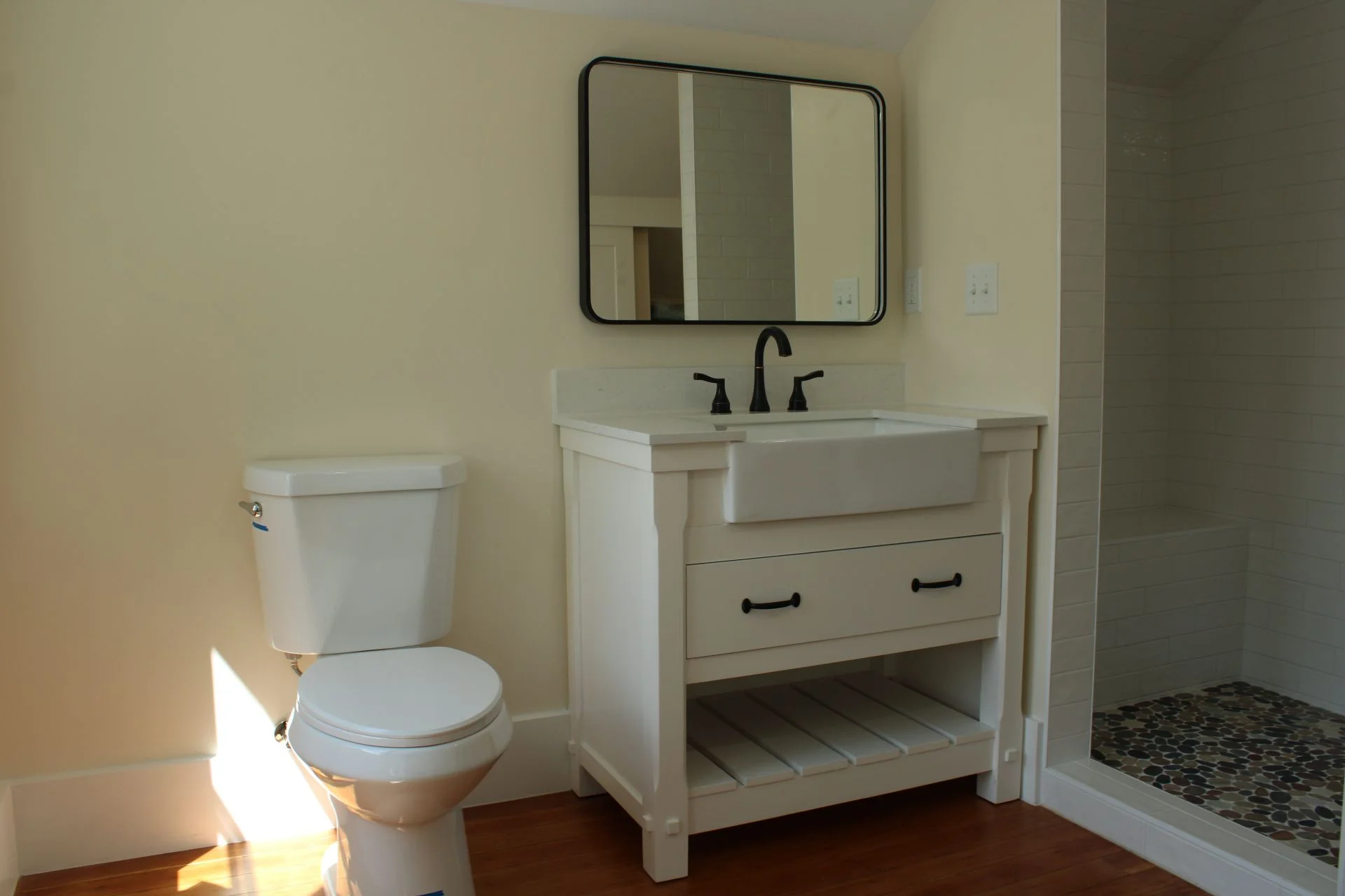 Modern farmhouse bathroom remodel by Buffalo Built LLC in Buffalo Wyoming, featuring a white apron sink vanity and custom tiled walk-in shower.