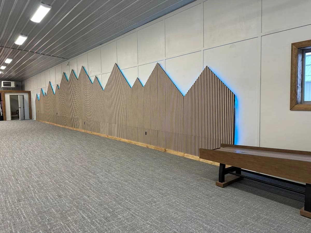 Custom mountain-shaped wood slat accent wall with blue LED backlighting built for Trailhead Student Ministry by Buffalo Built LLC.