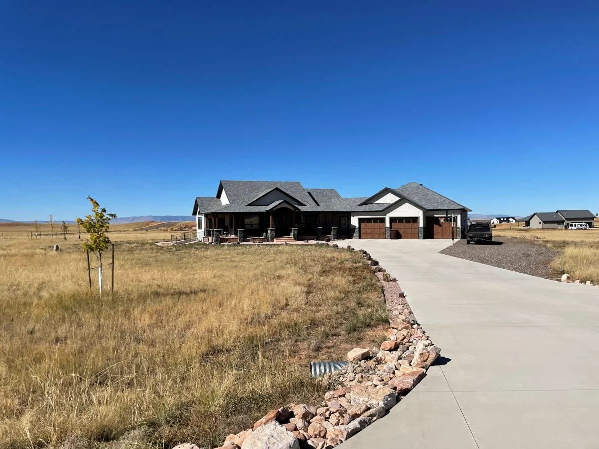 Completed luxury custom home featuring stone pillars, dark wood garage doors, and custom timber accents by Buffalo Built LLC in Laramie, WY.