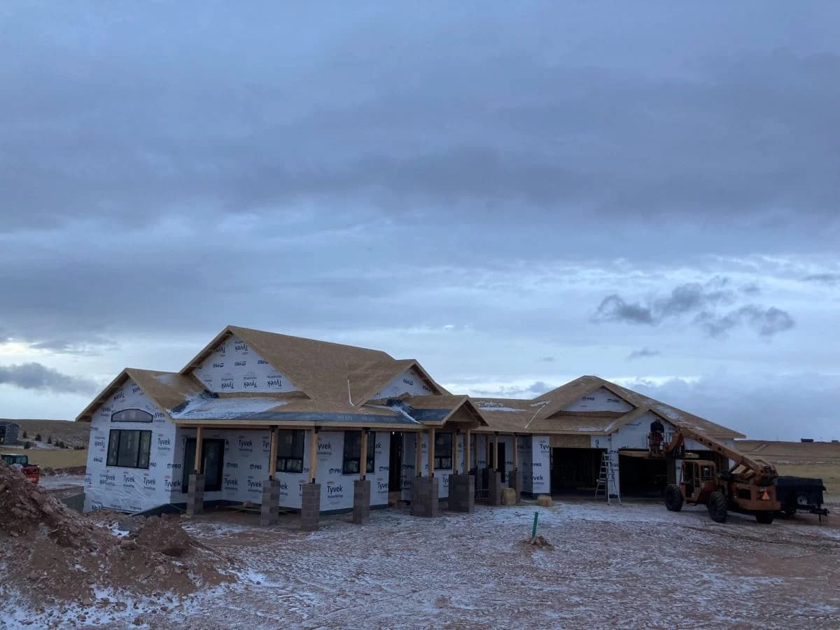 Expansive custom home construction site showing completed structural framing and house wrap by Buffalo Built LLC.