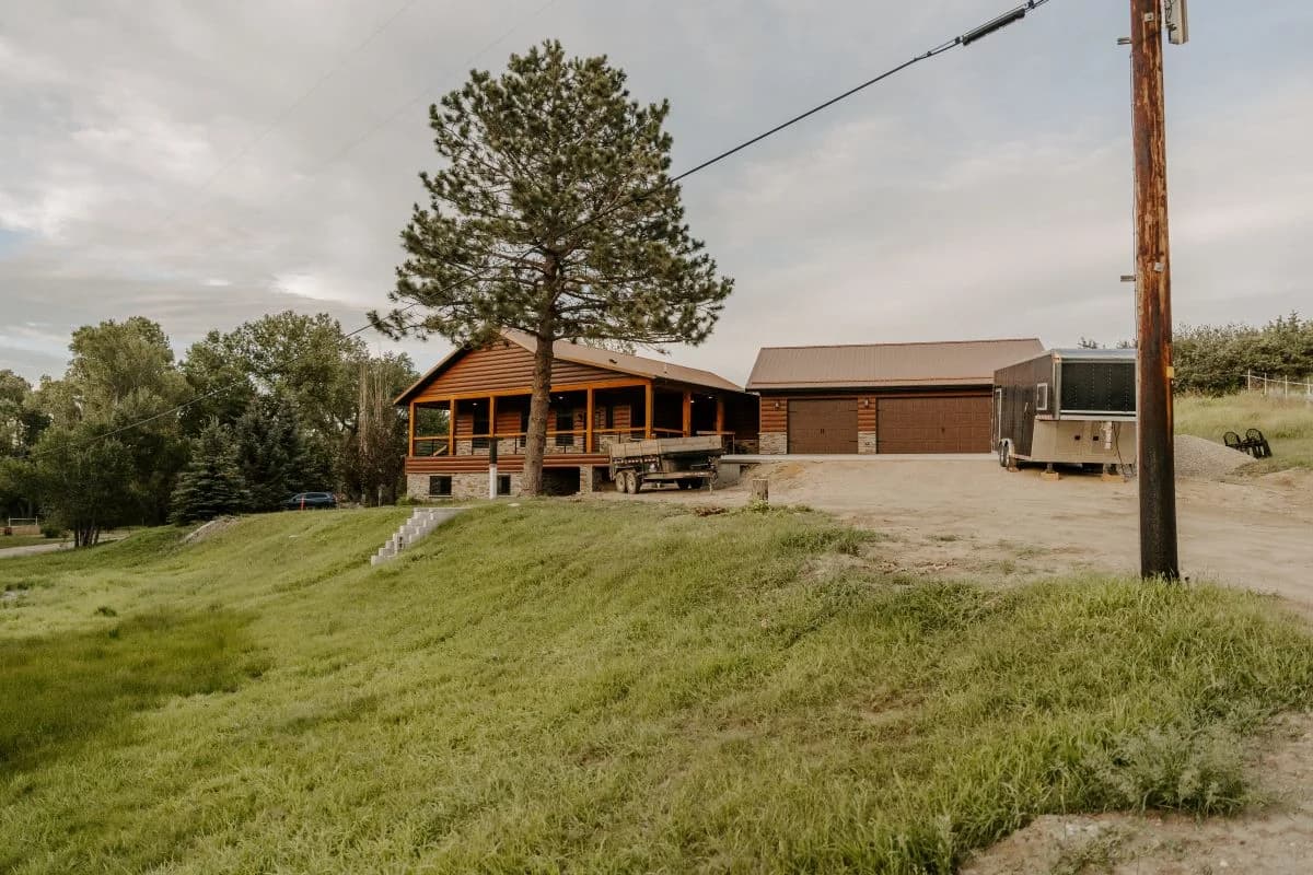 Completed design build rustic log home featuring a timber framed wrap-around porch by Buffalo Built LLC in Buffalo, WY.
