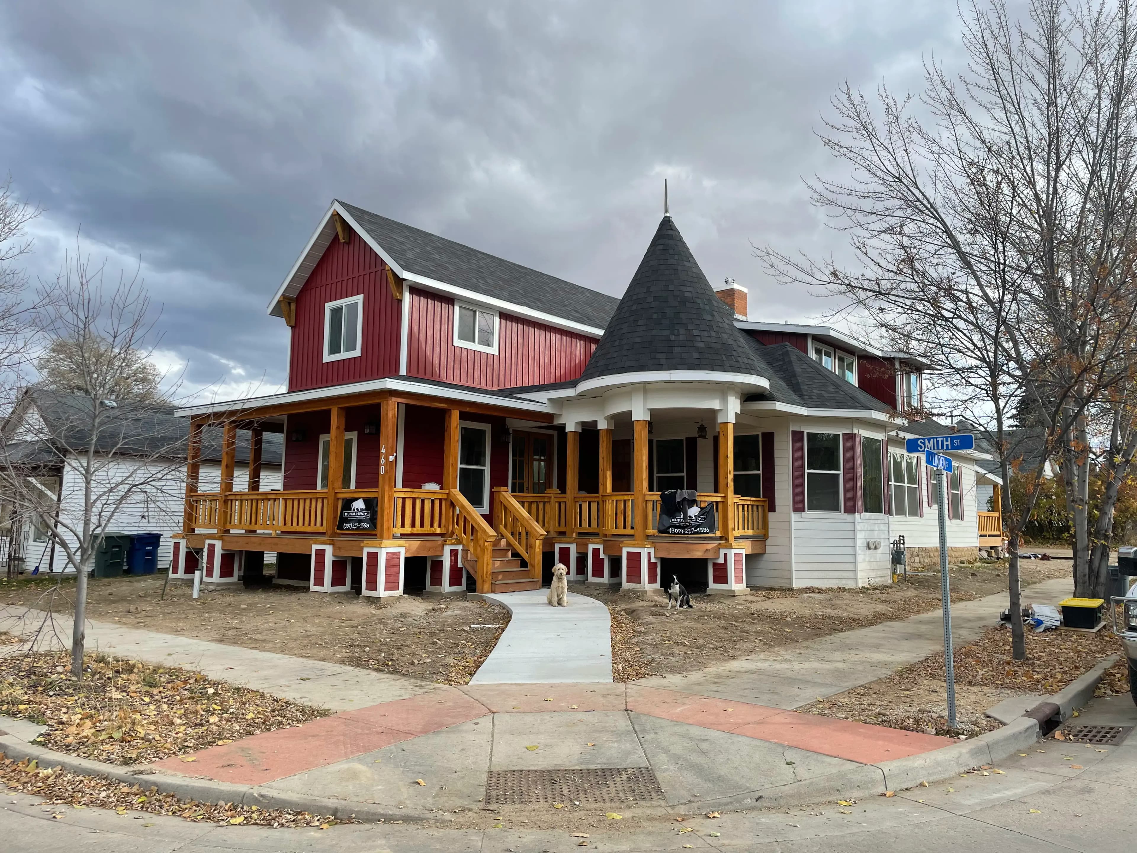 Two-story house addition featuring custom timber porch posts, decorative red vertical siding, and a unique turret roof architecture built by Buffalo Built LLC in Sheridan Wyoming.