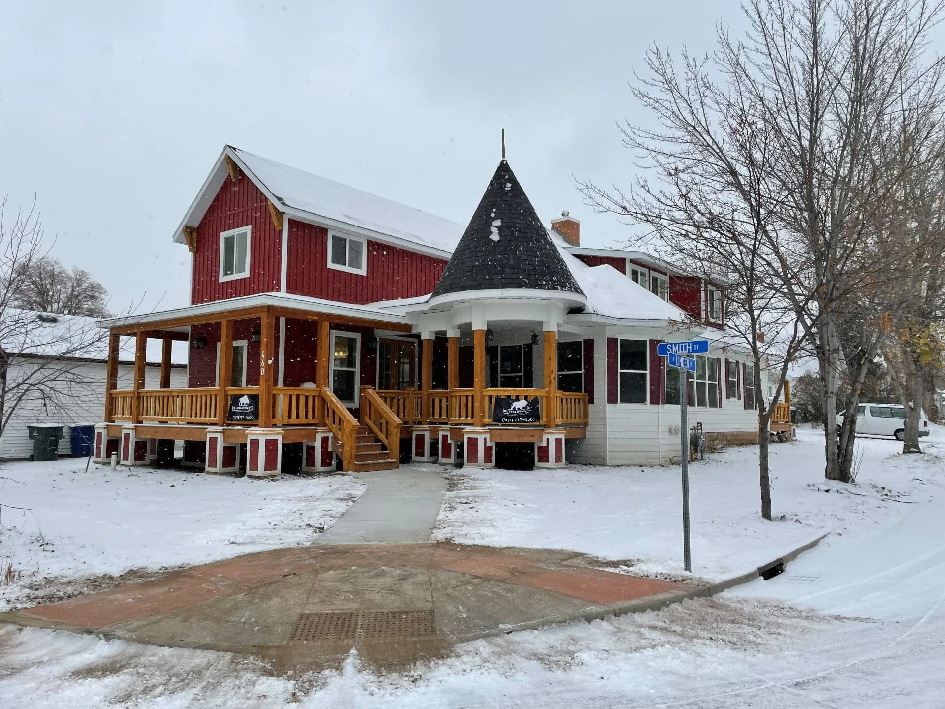 Large custom wrap-around covered porch featuring heavy timber posts, wood railings, and integrated stairs built by Buffalo Built LLC in Sheridan Wyoming.