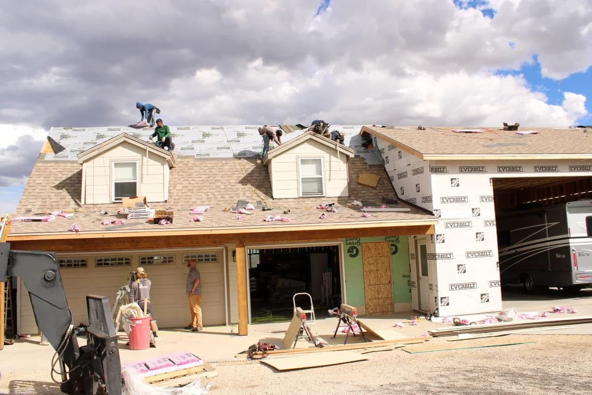 Construction crew framing a custom house extension and adding dormers to a residential garage addition.