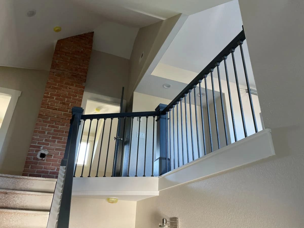 Interior view of a second-story loft addition completed by Buffalo Built LLC in Sheridan Wyoming, featuring vaulted ceilings and modern black metal staircase railings.