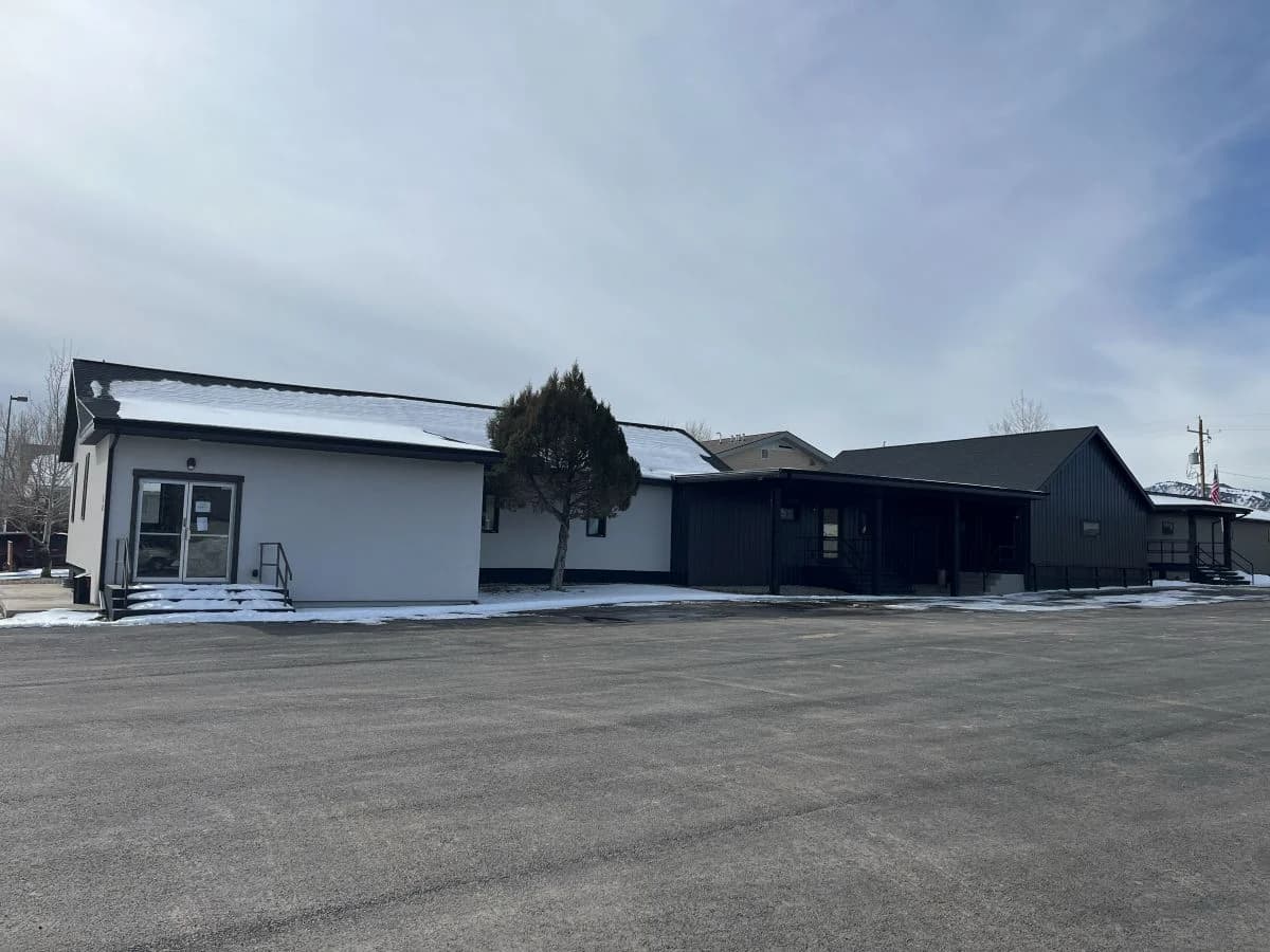 Completed commercial building expansion featuring sleek dark metal siding and new stucco additions by Buffalo Built LLC.