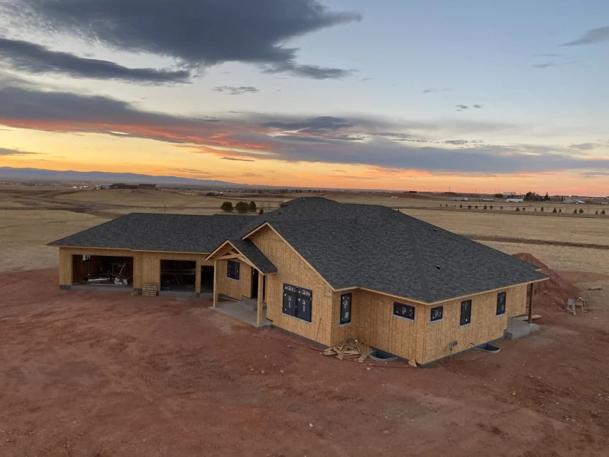 Completed residential building envelope with finished asphalt shingle roof and window installation by Buffalo Built LLC.