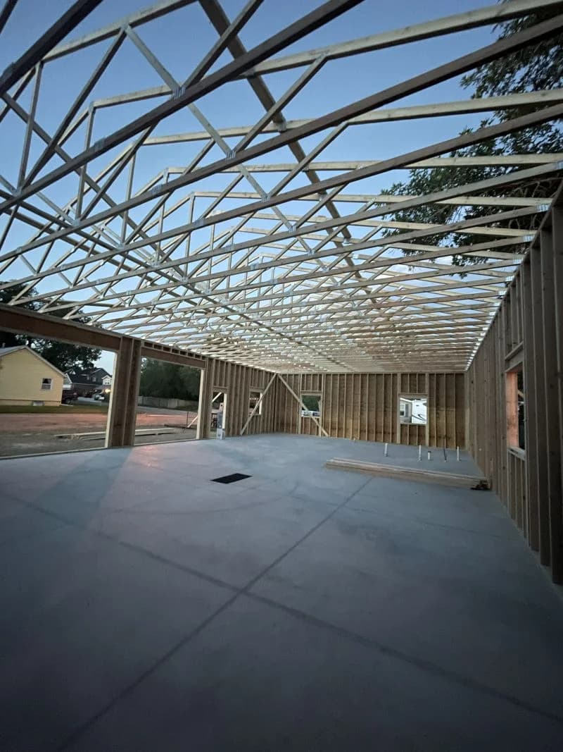 Active garage framing phase showcasing an extensive engineered roof truss system layout on a concrete slab by Buffalo Built LLC.