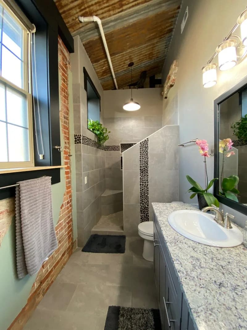 Modern industrial bathroom remodel featuring a custom tiled walk-in shower and granite vanity by Buffalo Built LLC.