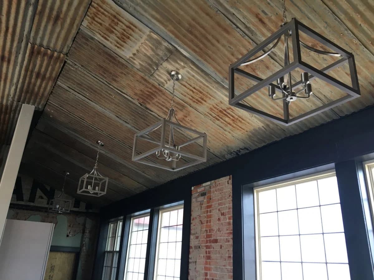 Custom interior finishes showcasing modern geometric pendant lights and a rustic corrugated metal ceiling by Buffalo Built LLC.