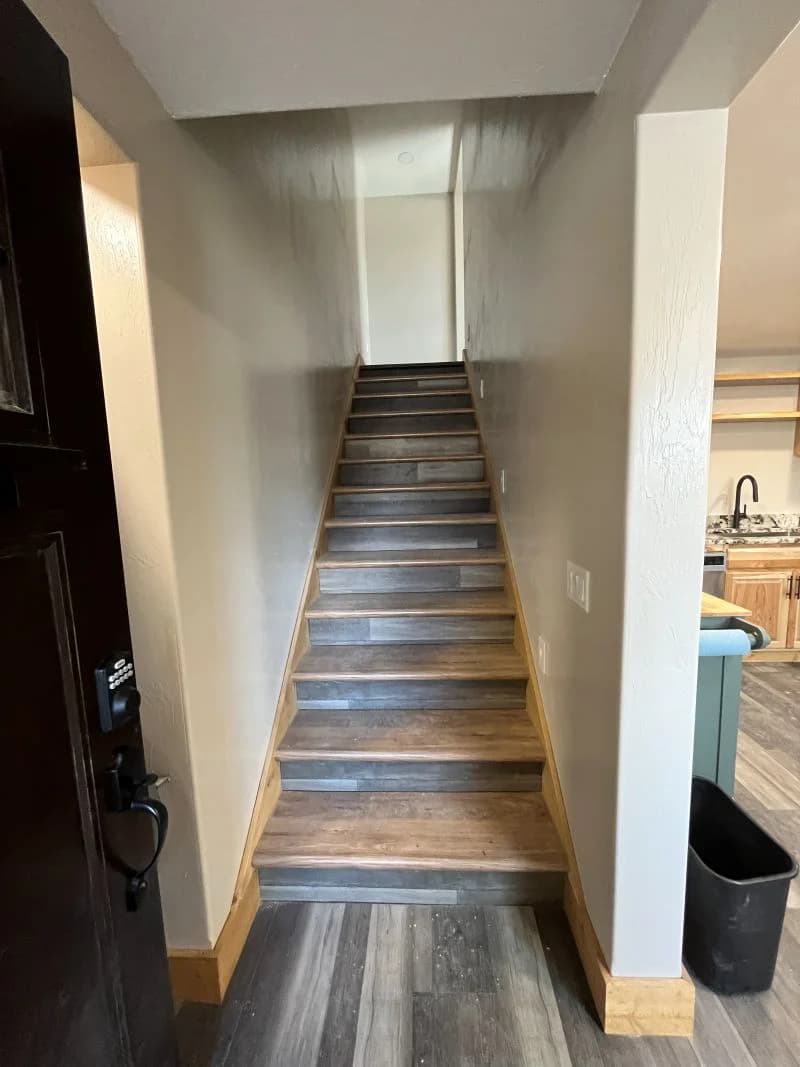 Custom staircase remodel featuring matching wood treads and natural baseboard trim by Buffalo Built LLC.